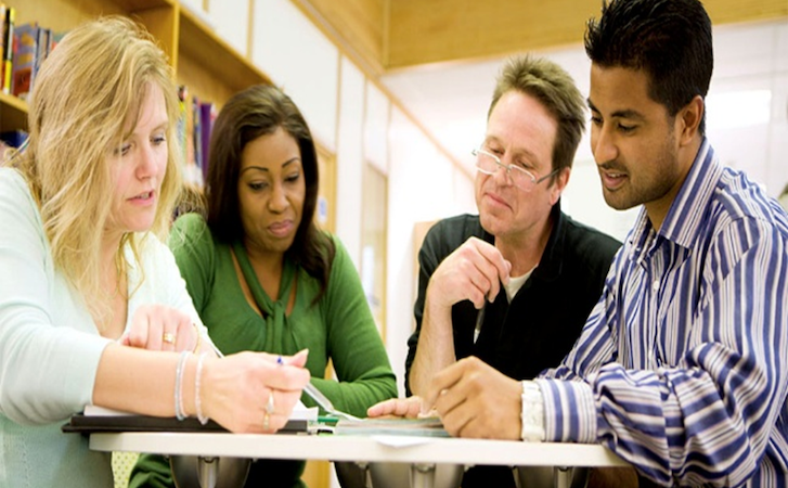 Four people sitting around a table in a library engaged in a study session